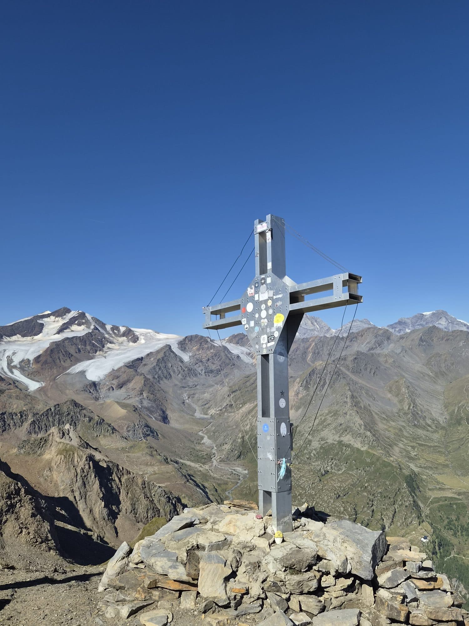 Gipfelkreuz vor vergletscherten Bergen